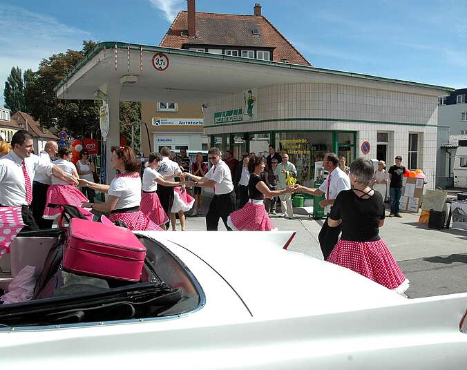 Menschen vor alter Tankstelle