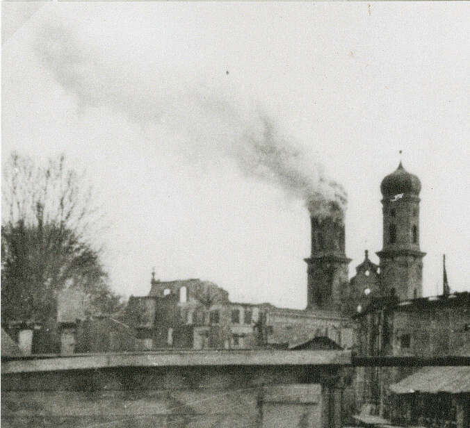 historische Aufnahme Friedrichshfen: zwei Kirchtürme, einer raucht vor zerbombter Stadt